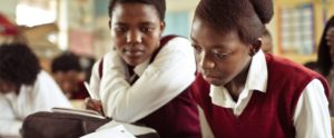 Two girls study a textbook in a rural African school.