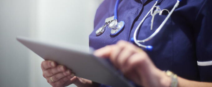 Torso of nurse using digital tablet