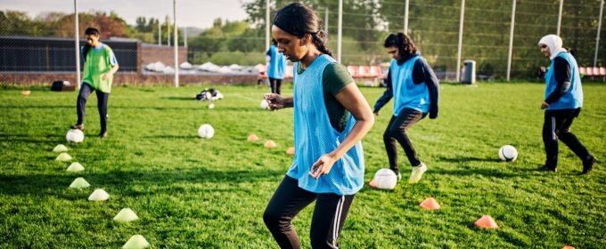 Several women practicing football on a grass field