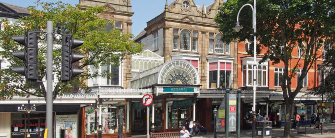 People walking on lord street in Southport, Merseyside in front of the historic wayfarers shopping arcade