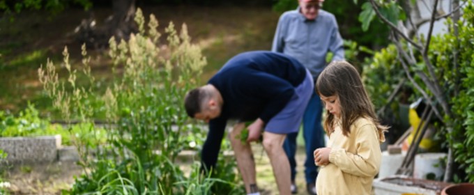 Child, adult, and elderly man in a garden.