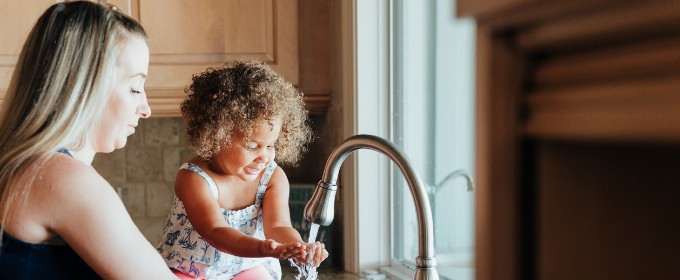 Woman and young girl washing their hands at the sink