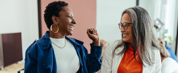 Two women are looking at each other laughing