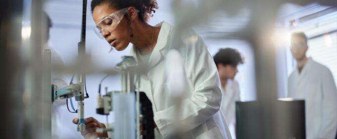 A female scientist in a lab examines a piece of laboratory equipment.