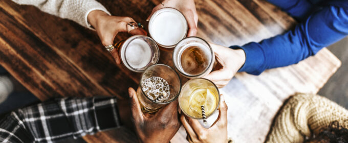 Image of 5 drinks being held, combination of beer and soft drinks